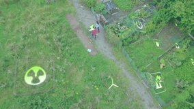 Drone ascending above allotment as couple walking along gravel path under floating energy icons. Sustainability, eco-friendly, renewable, agriculture, urban gardening, environmental awareness - Powered by Shutterstock - Get 15% off with code: PIKWIZARD15