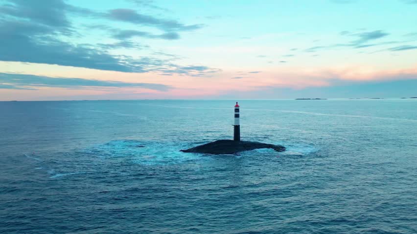 aerial footage showcasing a solitary lighthouse amidst the serene waters near the iconic Atlantic Ocean Road in Norway, bathed in the soft hues of a twilight sky.