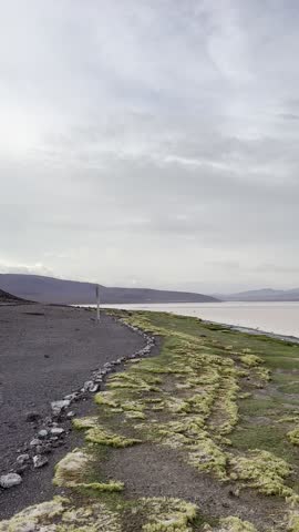 Laguna Colorada In Bolivia Showing The Lake Surface With Pink And Orange Sky Reflected In The Water Against The Highland Landscape.