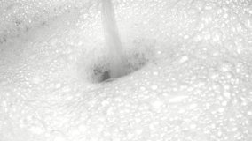 Water stream pours into a mass of soapy bubbles creating a small whirlpool. Excellent for a cleaning, washing, hygiene, or refreshing background. - Powered by Shutterstock - Get 15% off with code: PIKWIZARD15