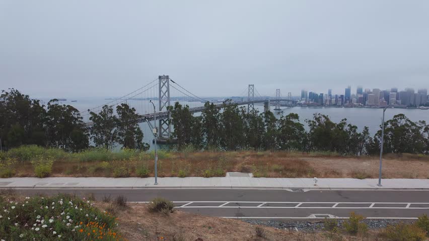 Video footage of the Bay Bridge and San Francisco skyline from Treasure Island, California, USA. Dynamic cityscape with skyscrapers in fog and iconic bridge spanning the bay waters