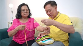 Senior woman knitting colorful yarn and tries to teach her husband how to knit on the sofa - Powered by Shutterstock - Get 15% off with code: PIKWIZARD15