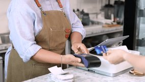 Senior entrepreneur cafe owner barista holds POS terminal while customer swipes creditcard, Asian retired female in apron smiling at counter, demonstrating cashless payment inside modern coffee shop - Powered by Shutterstock - Get 15% off with code: PIKWIZARD15