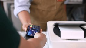 Senior entrepreneur cafe owner barista holds POS terminal while customer swipes creditcard, Asian retired female in apron smiling at counter, demonstrating cashless payment inside modern coffee shop - Powered by Shutterstock - Get 15% off with code: PIKWIZARD15