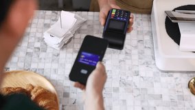 Senior entrepreneur cafe owner barista holds POS terminal while customer swipes creditcard, Asian retired female in apron smiling at counter, demonstrating cashless payment inside modern coffee shop - Powered by Shutterstock - Get 15% off with code: PIKWIZARD15