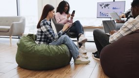 Collaborative office session featuring young adults discussing and working in relaxed, informal space. Room shows diverse team interacting, using technology, and fostering teamwork. - Powered by Shutterstock - Get 15% off with code: PIKWIZARD15