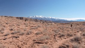 Sole Female Hiker Walking on Trail in Desert Landscape With Snow Capped Mountains in Background - Powered by Shutterstock - Get 15% off with code: PIKWIZARD15