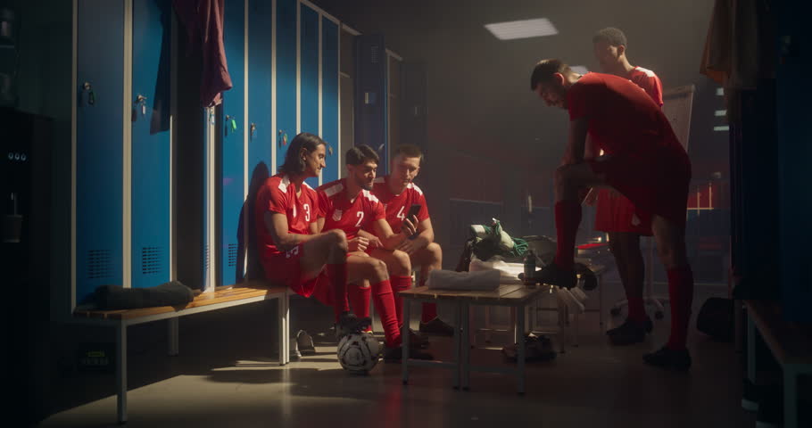 Soccer Players Sitting on a Locker Room Bench, Huddled Around a Smartphone. Team Bursts Into Celebration, Smiling and Cheering Together as They Watch the Screen. Sports Betting Concept