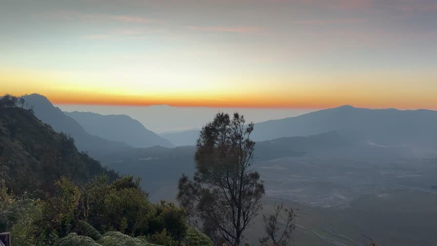 4k footage, view of magnificent Mount Bromo, Mount Batok, and its caldera with sea of sand, with sunrise sky in the early morning. Located in Bromo Tengger Semeru National Park, Indonesia.