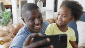 Father and daughter tapping selfie on phone initiating swirling emojis showing technology on couch. Family, bonding, joy, entertainment, digital, casual, vibrant - Powered by Shutterstock - Get 15% off with code: PIKWIZARD15