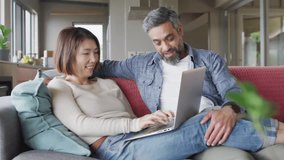 Seated couple typing laptop initiating emojis swirling around living room illustrating technology. Romantic, contemporary, vibrant, digital, cozy, interactive, casual - Powered by Shutterstock - Get 15% off with code: PIKWIZARD15