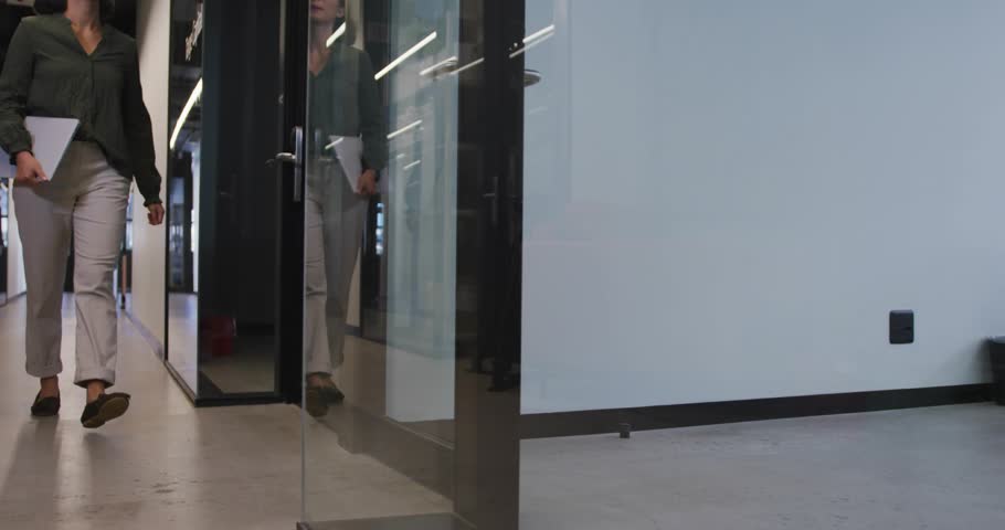 Businesswoman opening glass door while green tech icons streaming metrics showing sustainability. Corporate, innovation, futuristic, eco-conscious, professional, sustainable, minimalist