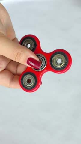 A woman twists a spinner toy on her finger. Red spinner in a woman's hand