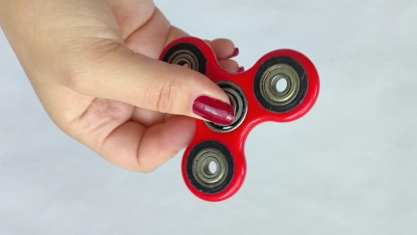A woman twists a spinner toy on her finger. Red spinner in a woman's hand