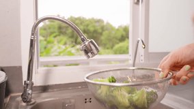 Hand Tossing Broccoli in Metal Strainer Above Sink in Slow Motion to Shake Off Water with Window Light in Background. - Powered by Shutterstock - Get 15% off with code: PIKWIZARD15