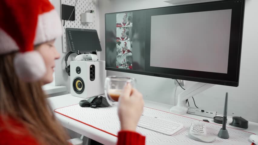 Woman drinking coffee at desk and editing AI generated images on computer screen. Cozy winter workspace with holiday spirit, freelance creativity and artificial design tools.