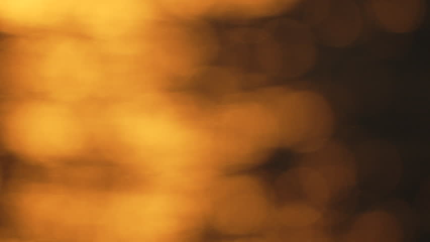 blurry, yellowish-orange sunset over water. The water appears to be rippling and the sky is filled with a warm, golden glow.