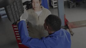 Technicians kneeling at auto wheel hub aligning wheel displaying torque HUD guiding nut fastening. Automotive, repair, diagnostics, digital, technology, teamwork, industrial - Powered by Shutterstock - Get 15% off with code: PIKWIZARD15