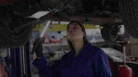 Female mechanic inspecting under vehicle by LED torch in auto shop, binary code fragments emerging. Industrial, technology, maintenance, futuristic, engineering, precision, workspace - Powered by Shutterstock - Get 15% off with code: PIKWIZARD15