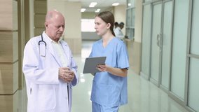 Hospital, healthcare, medical, doctor, nurse using tablet to review patient information, senior male mentoring young student trinee in hallway, technology helps improve teamwork efficiency diagnosis - Powered by Shutterstock - Get 15% off with code: PIKWIZARD15