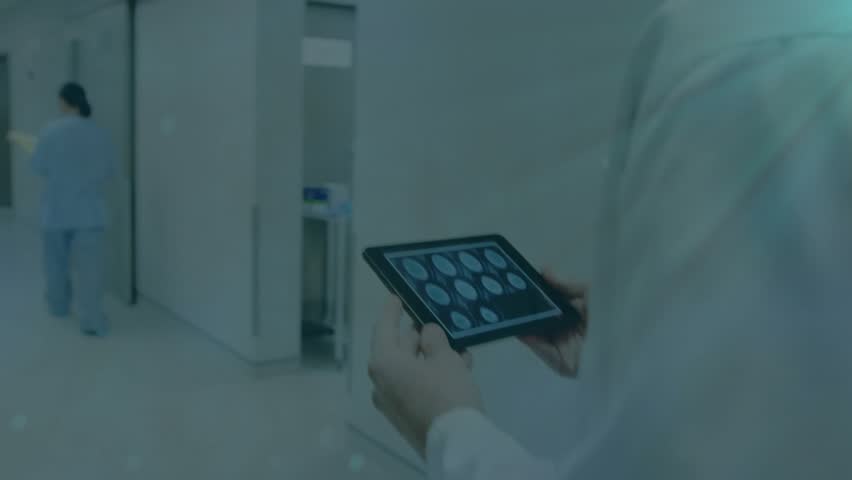 Doctor holding tablet and scrolling while walking hospital hall displaying cyan network data flow. Medical technology, healthcare, connectivity, digital health, professional, collaboration, futuristic - Powered by Shutterstock - Get 15% off with code: PIKWIZARD15