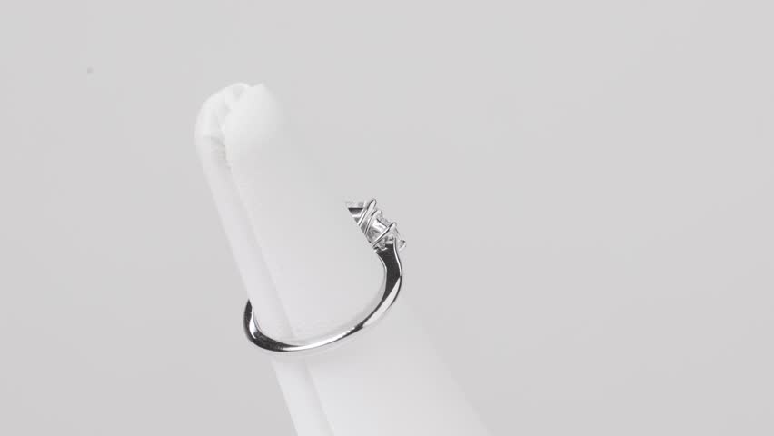 Close-up of a square diamond ring on a jewelry stand, rotating on a white backdrop.
