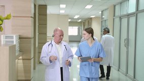 Hospital, healthcare, medical, doctor, nurse using tablet to review patient information, senior male mentoring young student trinee in hallway, technology helps improve teamwork efficiency diagnosis - Powered by Shutterstock - Get 15% off with code: PIKWIZARD15