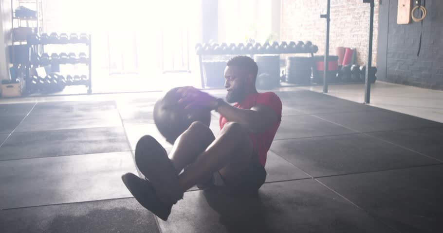 Trainer initiating Russian twist with medicine ball, showing core strength with rotation arrows. Strength, fitness, core, workout, industrial, dynamic, balance