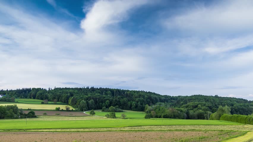 Agricultural fields with crops in the countryside in a hilly valley under a cloudy sky