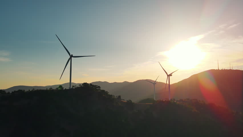 Wind farm silhouettes against a sunrise horizon, aerial view. Clean electricity supports grid decarbonization and climate targets