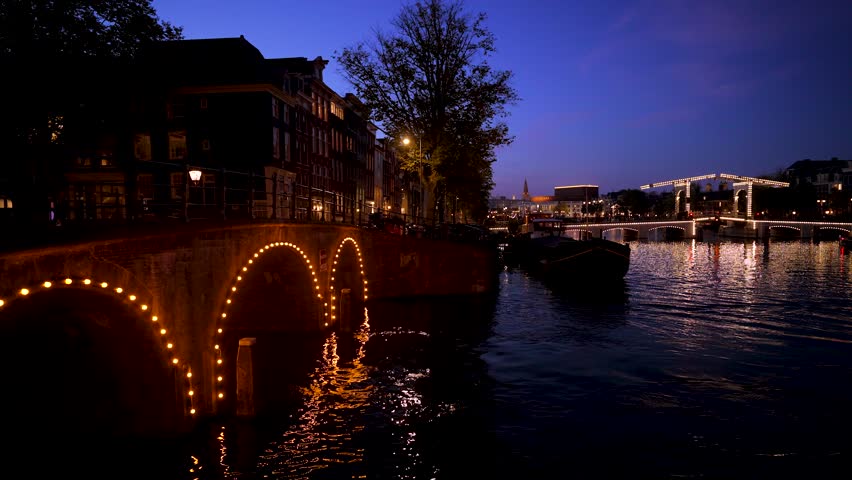 Illuminated Magere Brug (Skinny Bridge) over the Amstel River and Canals of Amsterdam after Sunset
