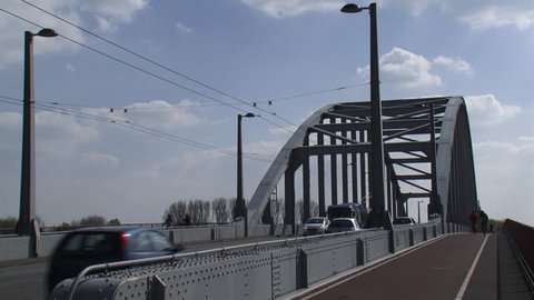 Traffic, cyclist and trolleybus over John Frost Bridge. A trolleybus draws its electricity from overhead wires.