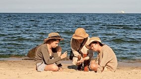 A mother and children traveling to the sea, vacationing with children in nature, searching for something in the sand and looking through a magnifying glass, exploring fossils in the sand - Powered by Shutterstock - Get 15% off with code: PIKWIZARD15