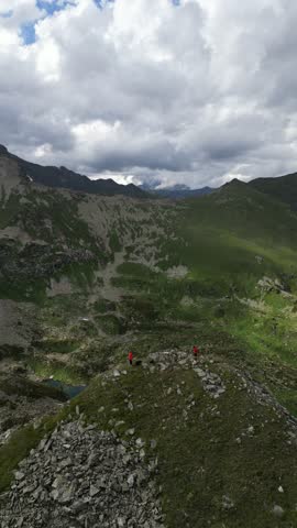 Tourists at the top of the mountain range are surrounded by the Arkhyz mountains, shrouded in snow and melting glaciers, with views of green meadows and lakes below