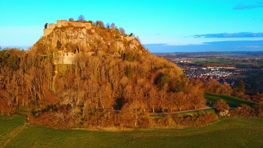 Aerial view of a hill with the ruins of the Hohentwil castle on its top against a blue sky