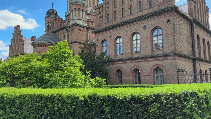 West building, or Seminary wing and Three Hierarchs Church in Chernivtsi National University complex, former Residence of the Metropolitans, Ukraine, view while vertical panning in sunny windy day
