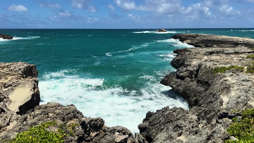 Dramatic waves crash against rocky cliffs in sunny Oahu, Hawaii