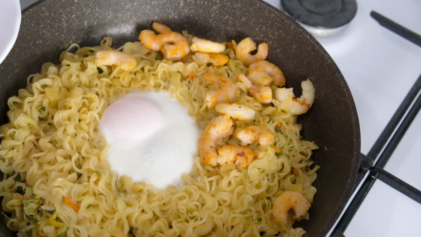 Chef woman cooking sprinkling greenery on noodles with egg and shrimp in frying pan. Preparing Asian dish on gas stove. Cook fresh food, domestic homemade recipe. Culinary, cuisine, fry cook noodles.