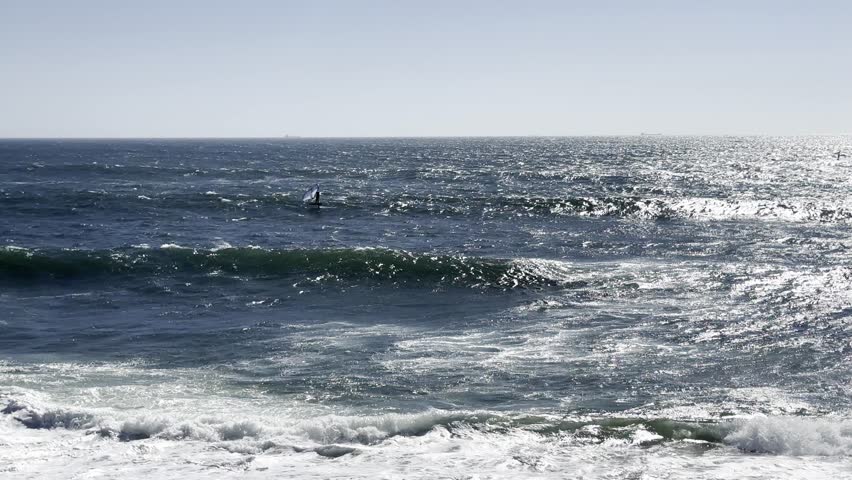 surfer rides the ocean waves under clear skies. The scene captures action, adventure, and the spirit of water sports in a natural coastal environment.