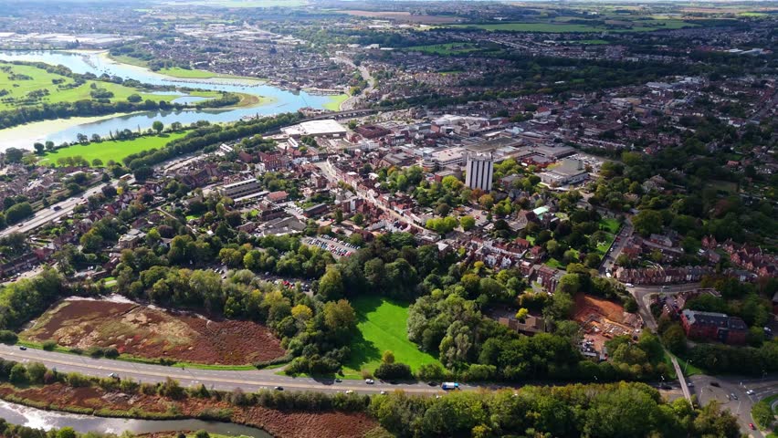 Aerial drone pans right over Fareham town, capturing river, trees, roads, and autumn colours glowing warmly in golden sunset light across the scenic English countryside landscape.