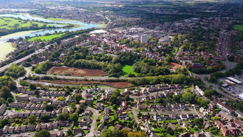 Aerial drone pans left over Fareham town centre, capturing river, trees, roads, and autumn colours glowing warmly in golden sunset light across the scenic English landscape.