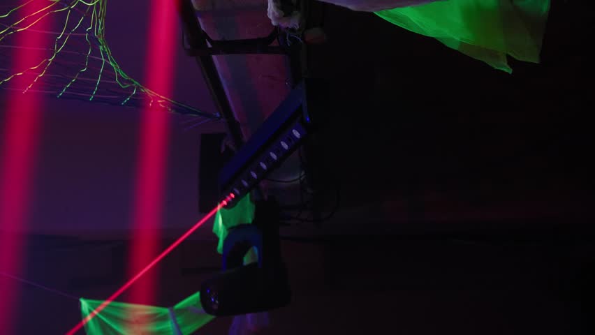 Laser stage lighting equipment projecting red and green beams during a concert, party, or music festival creating a vibrant and energetic atmosphere for entertainment and nightlife events
