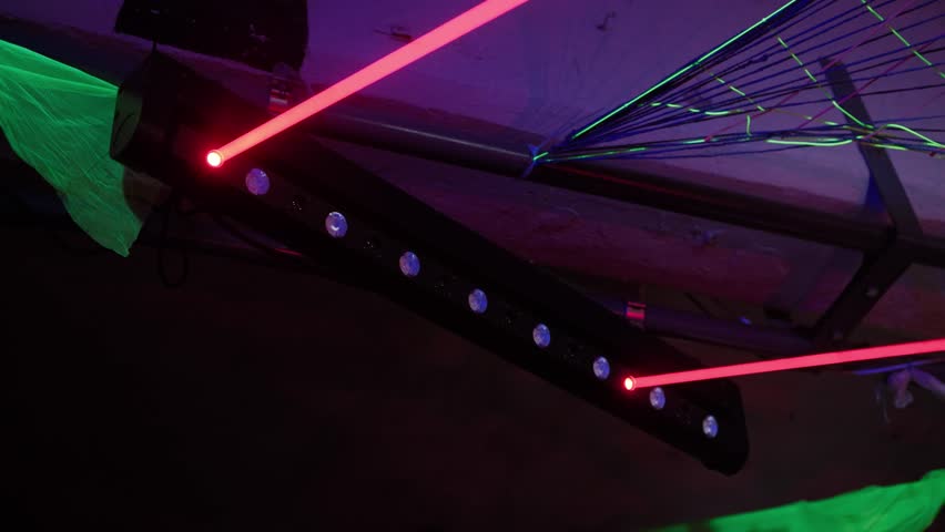 Red and green laser beams illuminating a dark space during a nightclub party or music festival. Powerful lighting equipment creates a vibrant and dynamic light show for entertainment