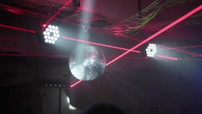 Shiny disco ball rotating and reflecting vibrant spotlights and red laser beams during a party, creating an energetic and festive atmosphere in a dark nightclub with atmospheric smoke - Powered by Shutterstock - Get 15% off with code: PIKWIZARD15