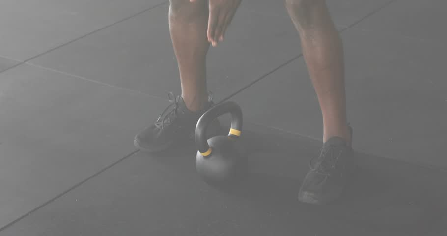 Fitness trainer gripping kettlebell and swinging kettlebell into front rack showing overlay metrics. Strength, workout, training, fitness, motion, athleticism, gym