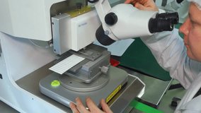 Quality control employee inspects a manufactured LED panel for defects using microscope. Research lab scientist examines an LED board through a microscope. Researcher in white coat at his workstation. - Powered by Shutterstock - Get 15% off with code: PIKWIZARD15