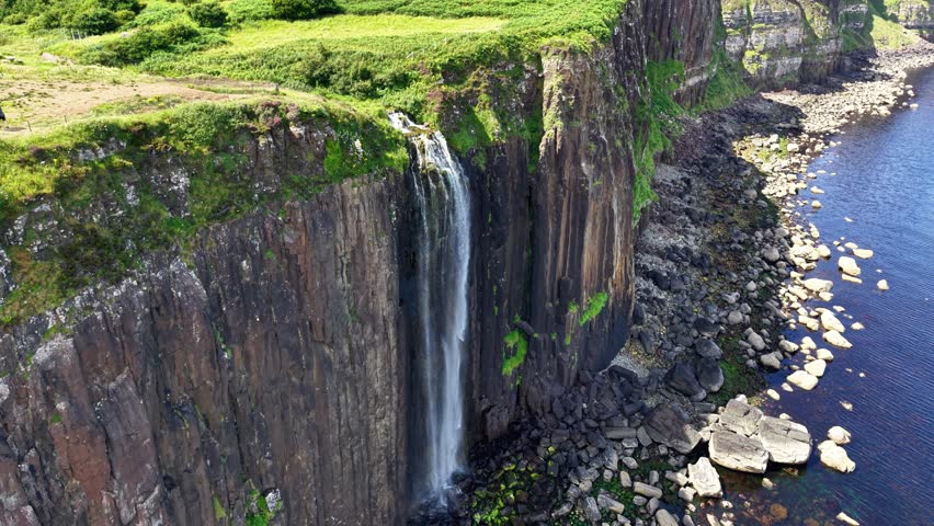 Majestic aerial view of a waterfall cascading down cliffs on the isle of Skye in Scotland revealing nature