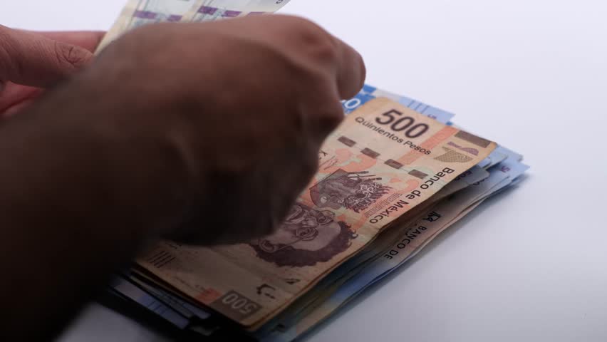 Hand sorting several Mexican peso bills. Slow motion close up