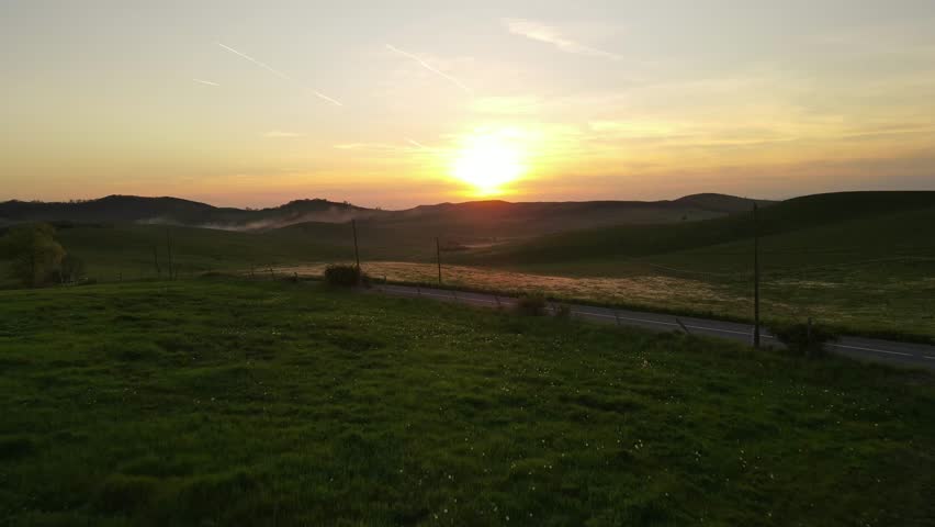 4K drone footage flying above mountains and rolling hills during a beautiful sunset.