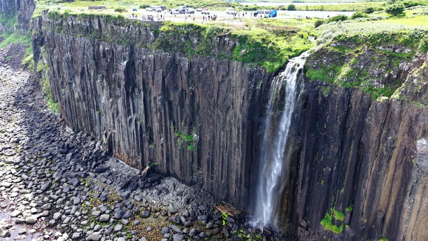 Breathtaking aerial view of a stunning waterfall on the Isle of Skye in Scotland surrounded by dramatic cliffs and lush nature